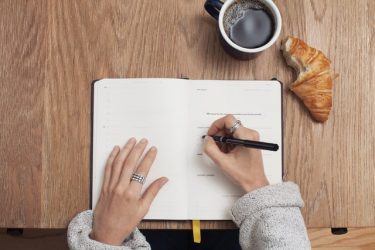 Fille écrit dans un cahier à la table