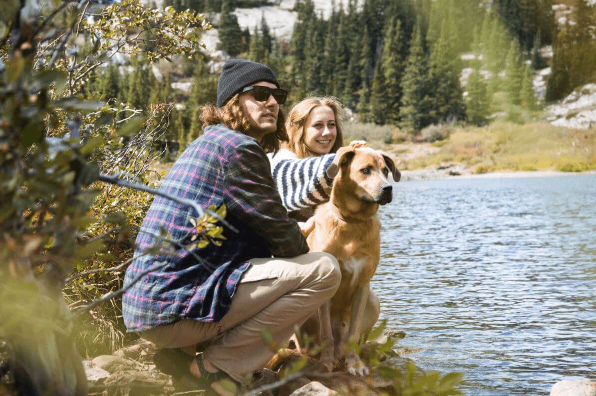 jeune couple avec un chien au bord d'un lac